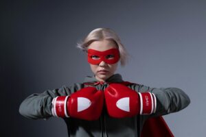 A teenager poses as a superhero wearing red boxing gloves and mask in a studio setting. Empowering and bold.