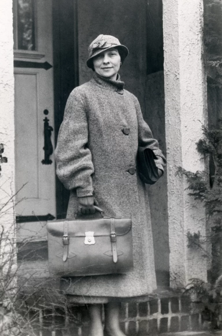 Black and white portrait of Elizebeth Smith Friedman in front of her house holding a briefcase