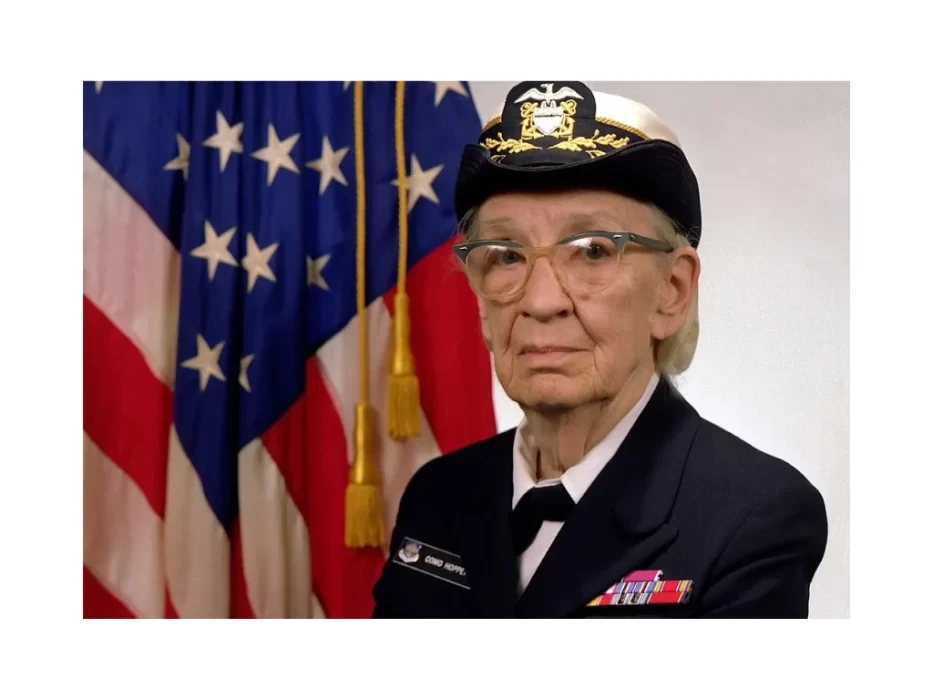 Image of Grace Hopper in uniform in front of American flag.